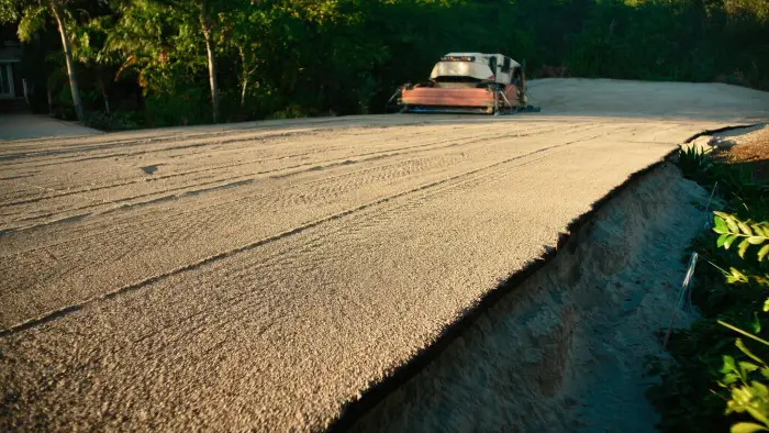 A compacted limerock base graded flat, with pale Florida sand visible in the cut edge