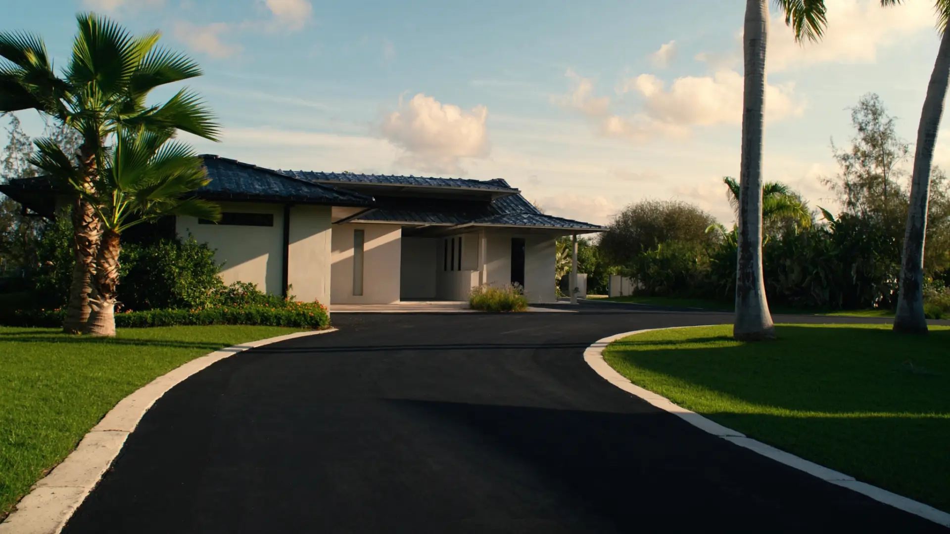 A freshly paved asphalt driveway curving up to a Florida home under late-afternoon light