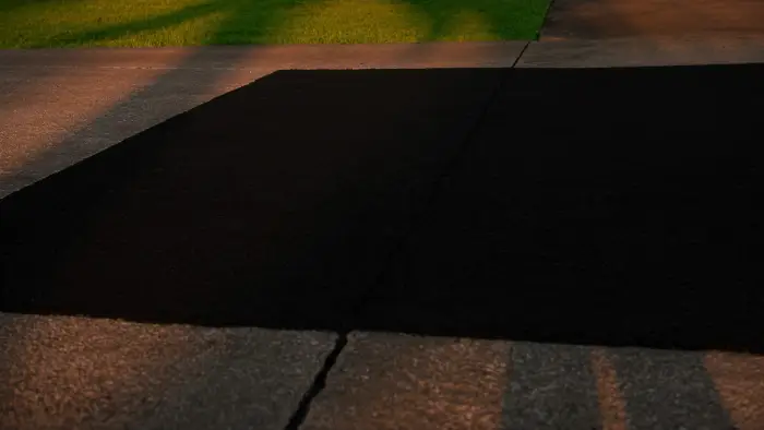 A saw-cut asphalt patch set flush into older weathered pavement